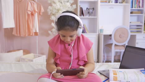 una niña jugando al teléfono en su habitación.
