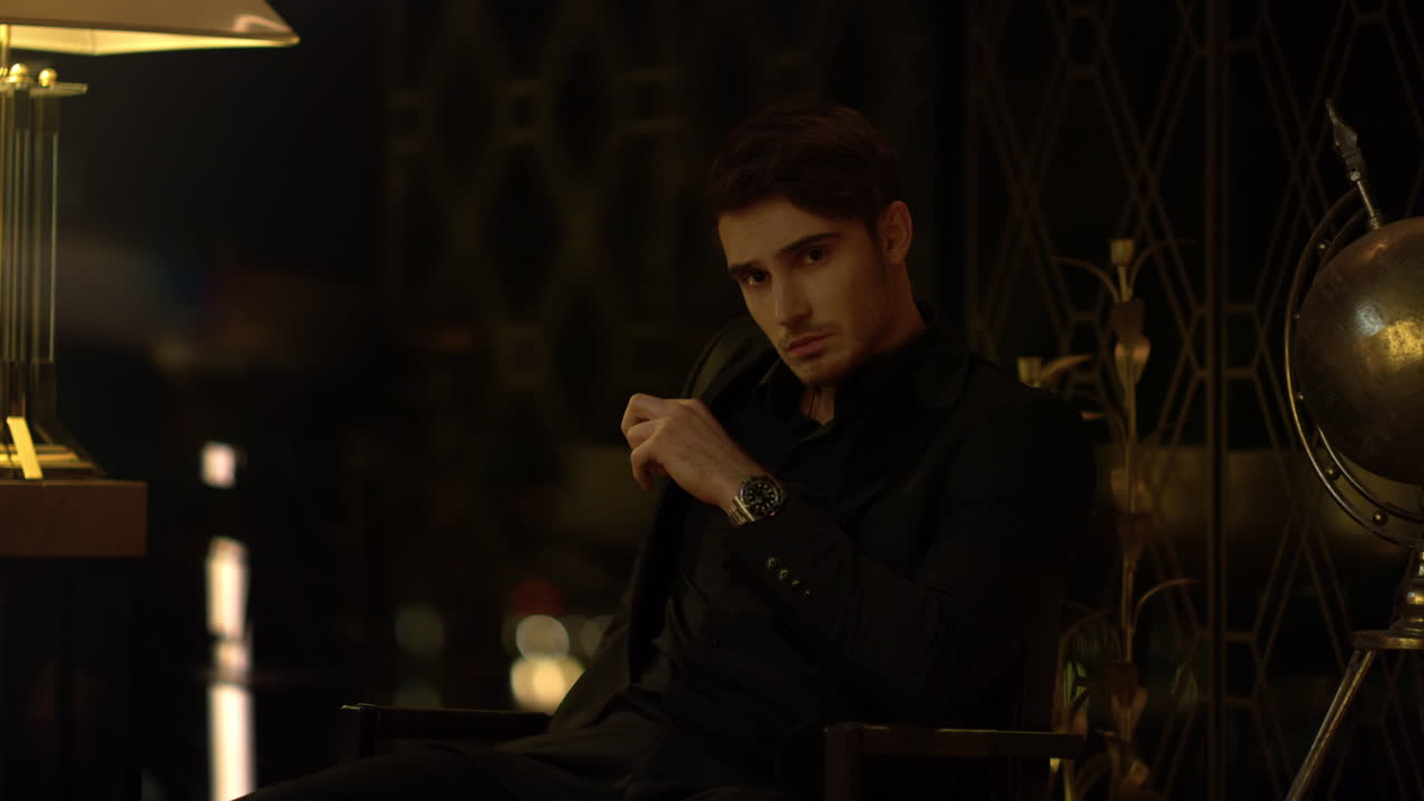 un chico sexy esperando a alguien en un cuarto oscuro, un hombre seguro mirando a su alrededor en el interior.