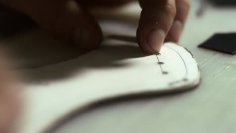 artisan man making holes. close up leather craftsman hands working with leather