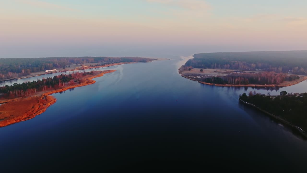 Lielupe river stretches calmly toward Baltic sea under soft pastel sunrise light