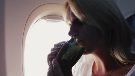 a woman eats a sandwich in the passenger cabin with appetite snack in the journey service on board