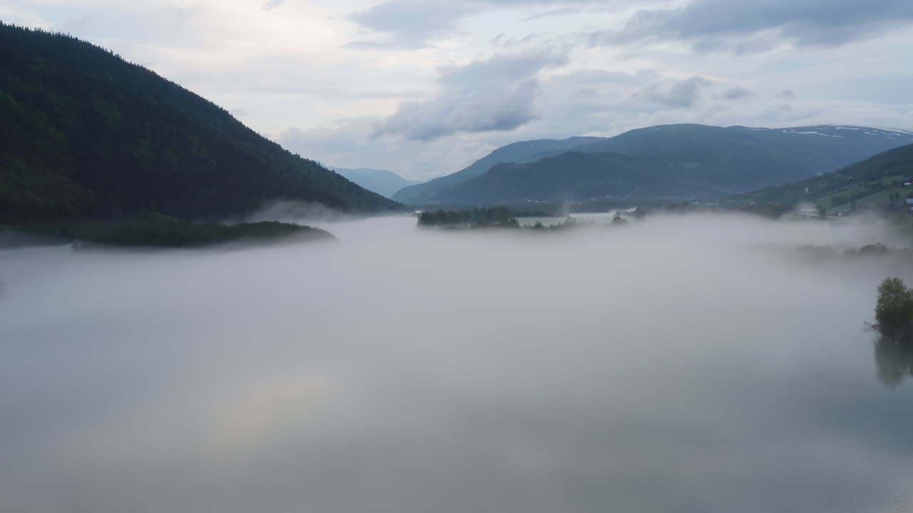 Flight over a foggy river. The mist is hanging low over the landscape creating a dark mystical mood over the whole scene.