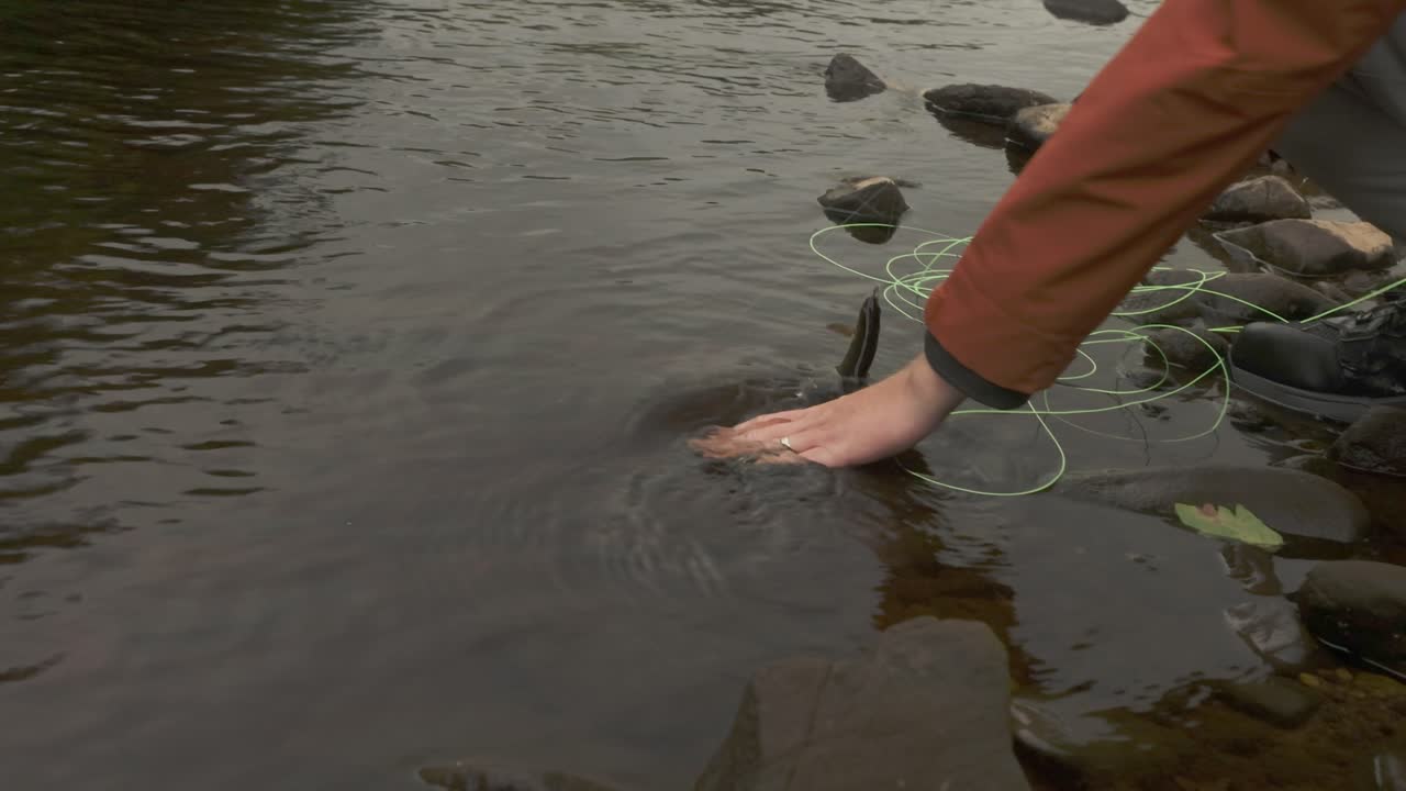 Hand-held shot of a fisherman picking up a caught brown trout to remove the lure