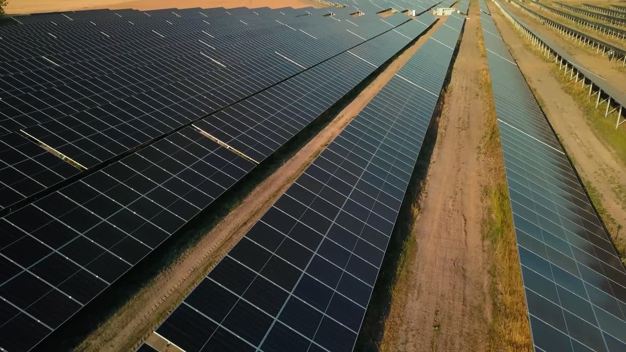 Drone nærmer sig solcelleanlæg på et stort landbrug for produktion af grøn, vedvarende energiforsyning.