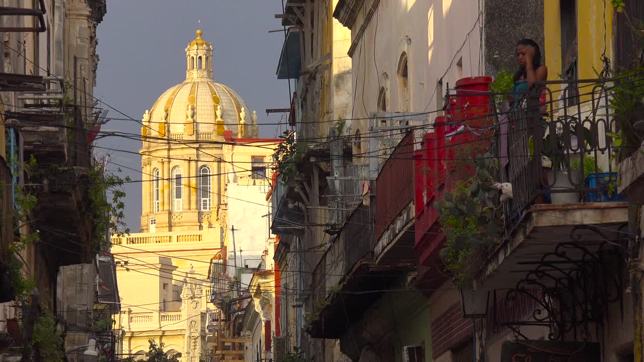 Una donna si affaccia da un balcone sulla città vecchia dell'Avana, Cuba