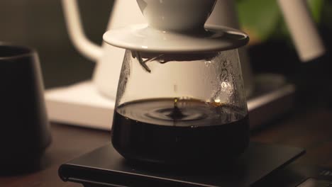 fresh brew of black coffee drip into glass carafe through ceramic dripper