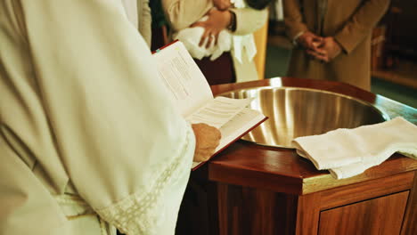 sacerdote católico lee la biblia antes del bautismo del bebé