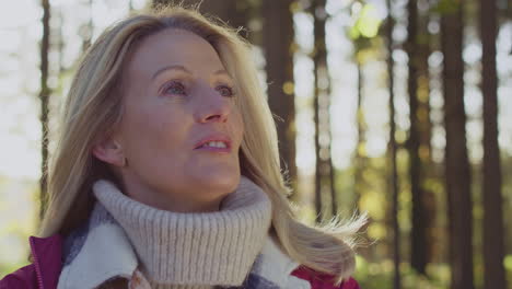 mature woman on relaxing walk through fall or winter countryside breathes in deeply - shot in slow motion