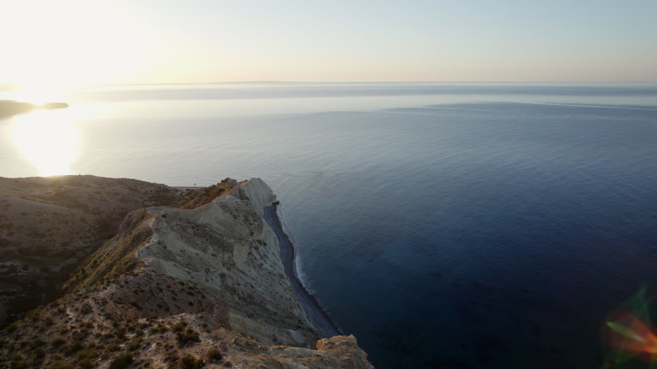 la belleza serena de chipre con esta impresionante imagen aérea capturando la puesta de sol sobre los dramáticos acantilados blancos y el tranquilo mar mediterráneo