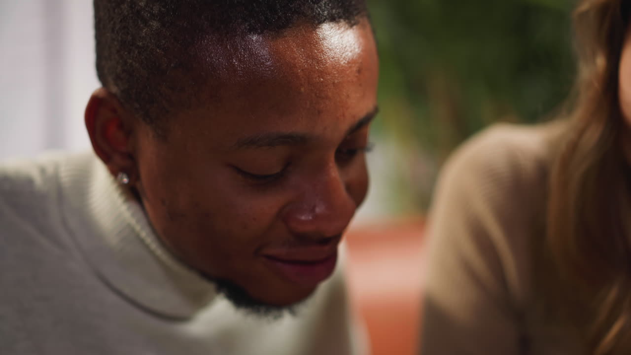 hombre afroamericano alegre asienta con la cabeza sentado cerca de una mujer blanca