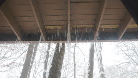 zoom out on icicles hanging from a porch