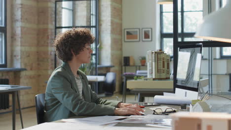 female architect working in a modern office with building models and blueprints