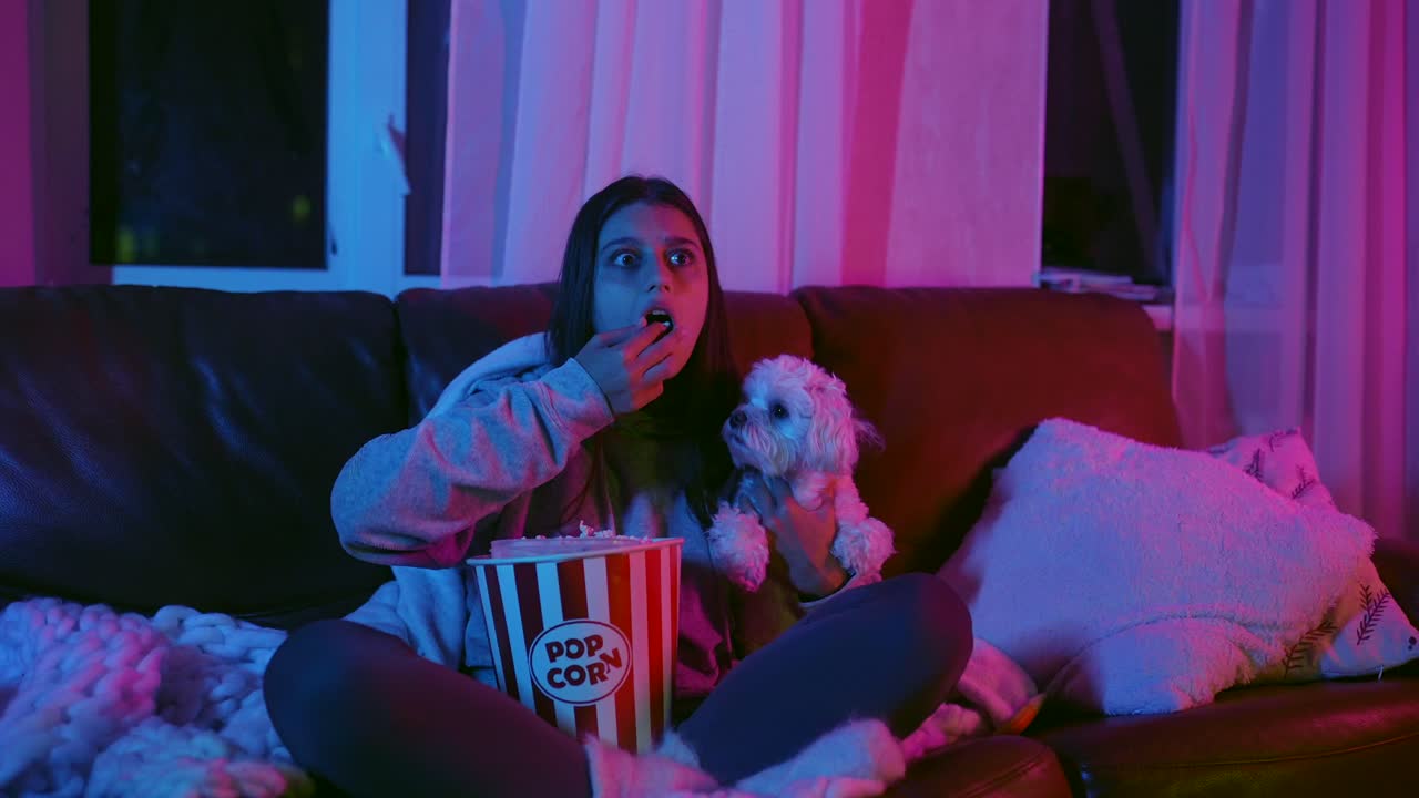adolescente a ver um filme com cão e pipocas.