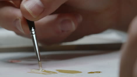 close up of artist twirling thin paintbrush and mixing different colors to create unique look for painting in naturally lit studio 4k