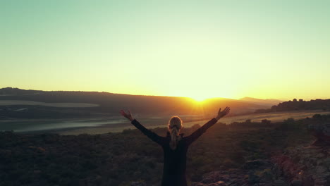 mujer disfrutando de una hermosa vista de amanecer o puesta de sol desde la cima de una montaña