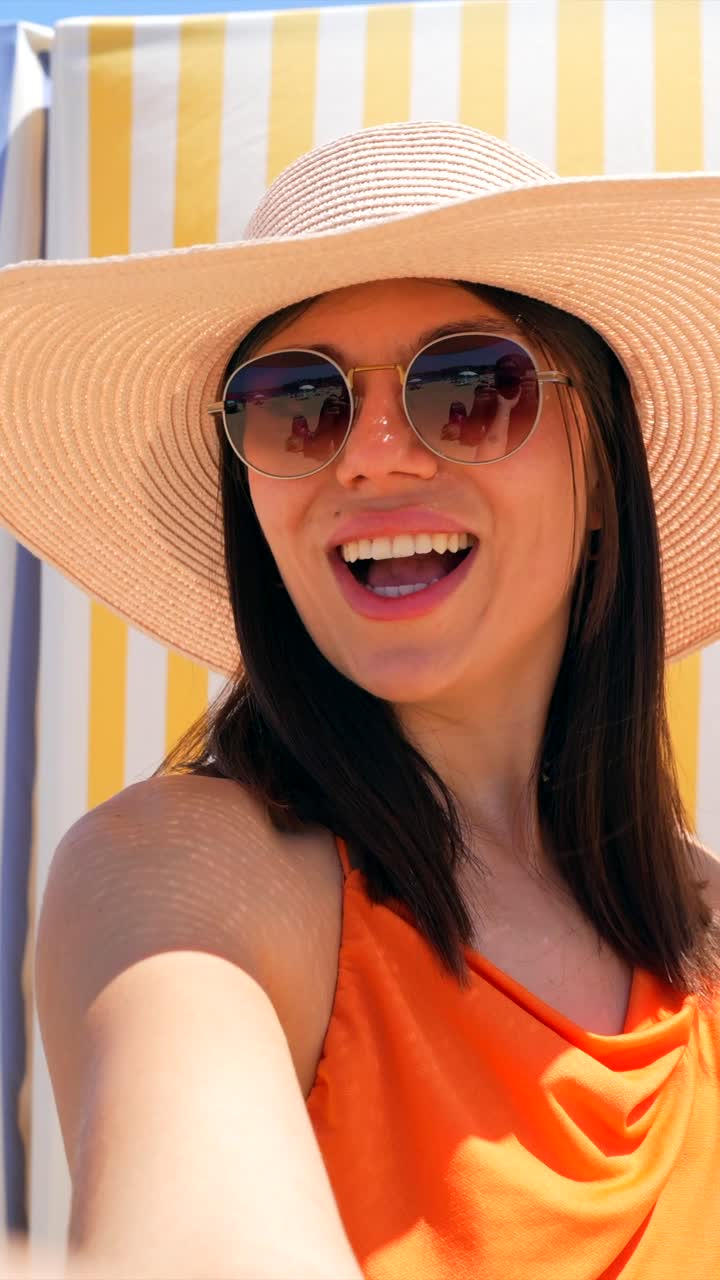 Woman wearing a hat and sunglasses at the beach