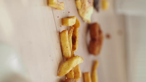 french fries and onion rings on a wooden board