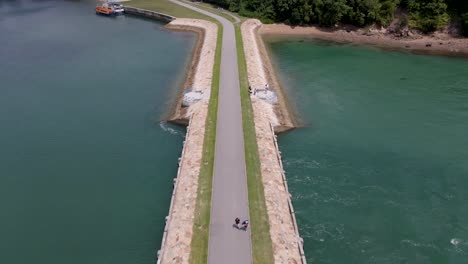 bridge over calm sea with beach and lush green forest at lazarus island in singapore