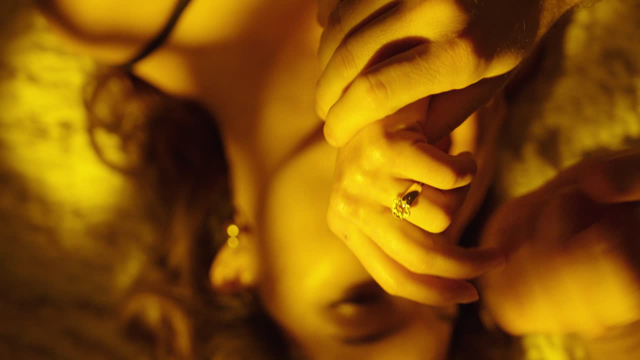Primo piano cinematografico dall'alto di un uomo che mette un anello al dito di una donna mentre sono sdraiati a letto. Concetto di fidanzamento, proposta di matrimonio, impegno, amore e momento romantico intimo.