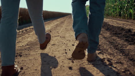 Primer-Plano-Zapatos-De-Granjeros-Caminando-Por-La-Carretera-De-Tierra-Vista-Trasera.-Trabajo-De-La-Industria-Agrícola.