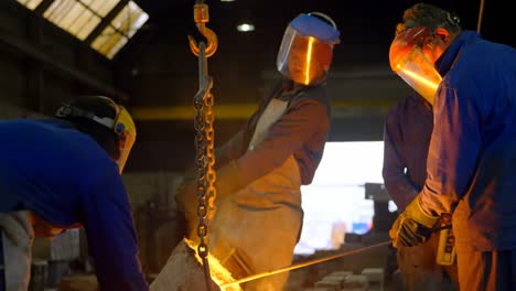 group of workers pouring molten metal in mold at workshop 4k