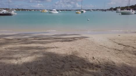 Una-Toma-Reveladora-Desde-La-Arena-De-Una-Playa-Hasta-Una-Vista-Panorámica-De-Algunos-Barcos-Anclados-En-Una-Playa-Tropical,-En-Mauricio