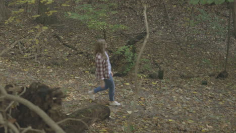 wide shot of a young woman walking down a trail in the woods