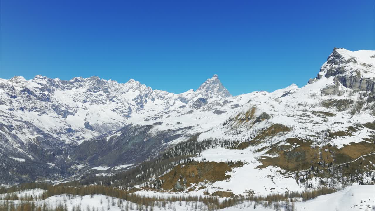 Snow-capped Matterhorn or Cervino and Alpine landscape near Cheneil, Valtournenche, clear blue sky, winter scenery, Italy. Aerial drone, copy space