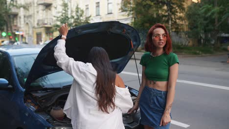 two women helping with broken down car