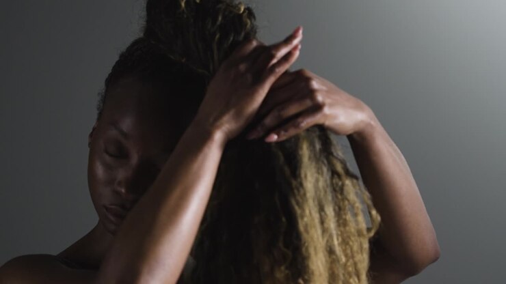 Studio Shot Of Woman Wearing Gym Fitness Clothing Putting Up Hair Before Exercise