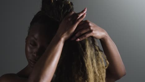 studio shot of woman wearing gym fitness clothing putting up hair before exercise