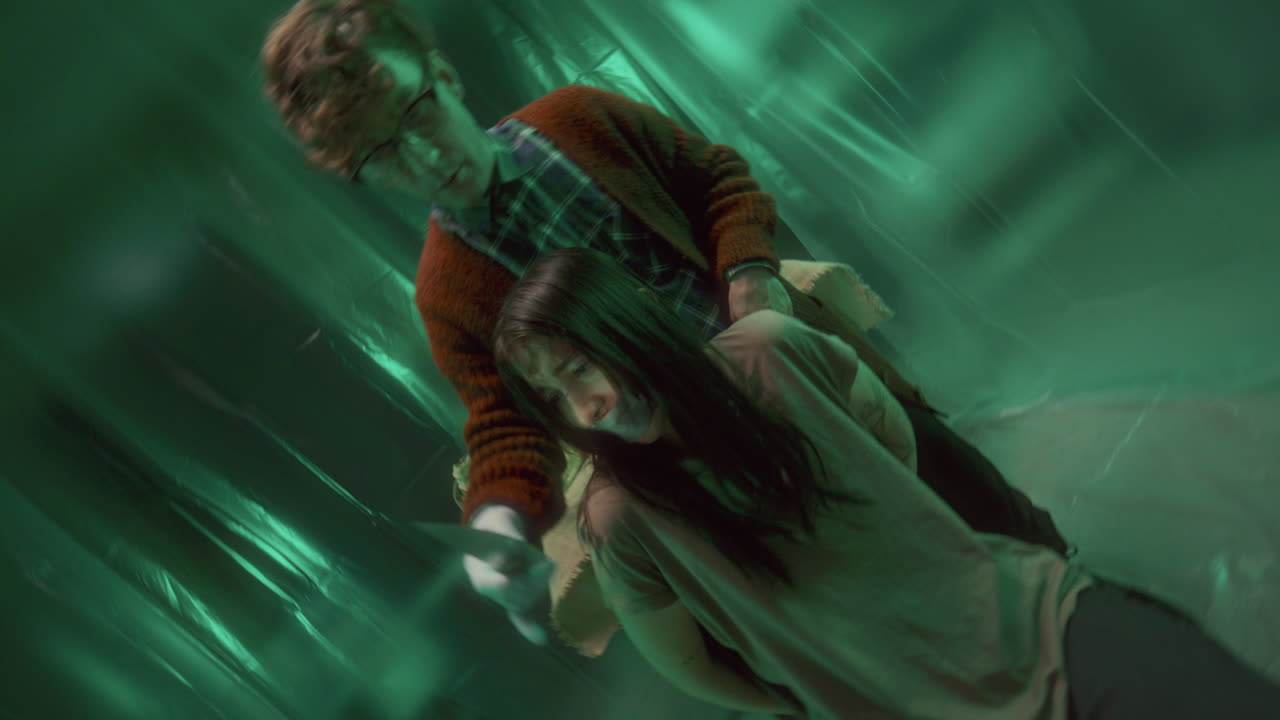 imagen de un loco intimidando a un rehén atado con un cuchillo en una habitación espeluznante.