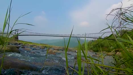 isolated iron suspension bridge over flowing river with mountain and blue sky background at morning video is taken at nongjrong meghalaya india