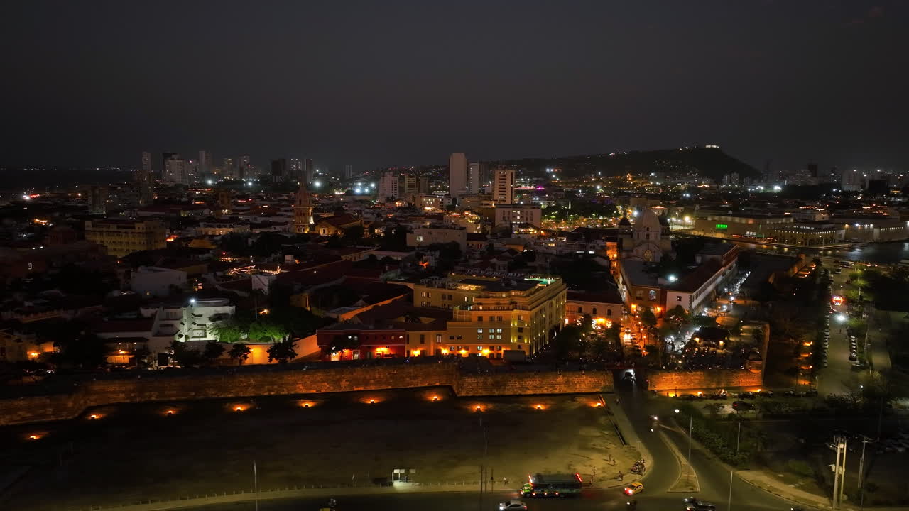 vista aérea frente al distrito centro iluminado, noche en cartagena, colombia - seguimiento, disparo de drones