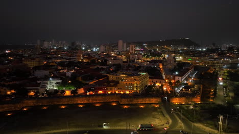 vista aérea frente al distrito centro iluminado, noche en cartagena, colombia - seguimiento, disparo de drones