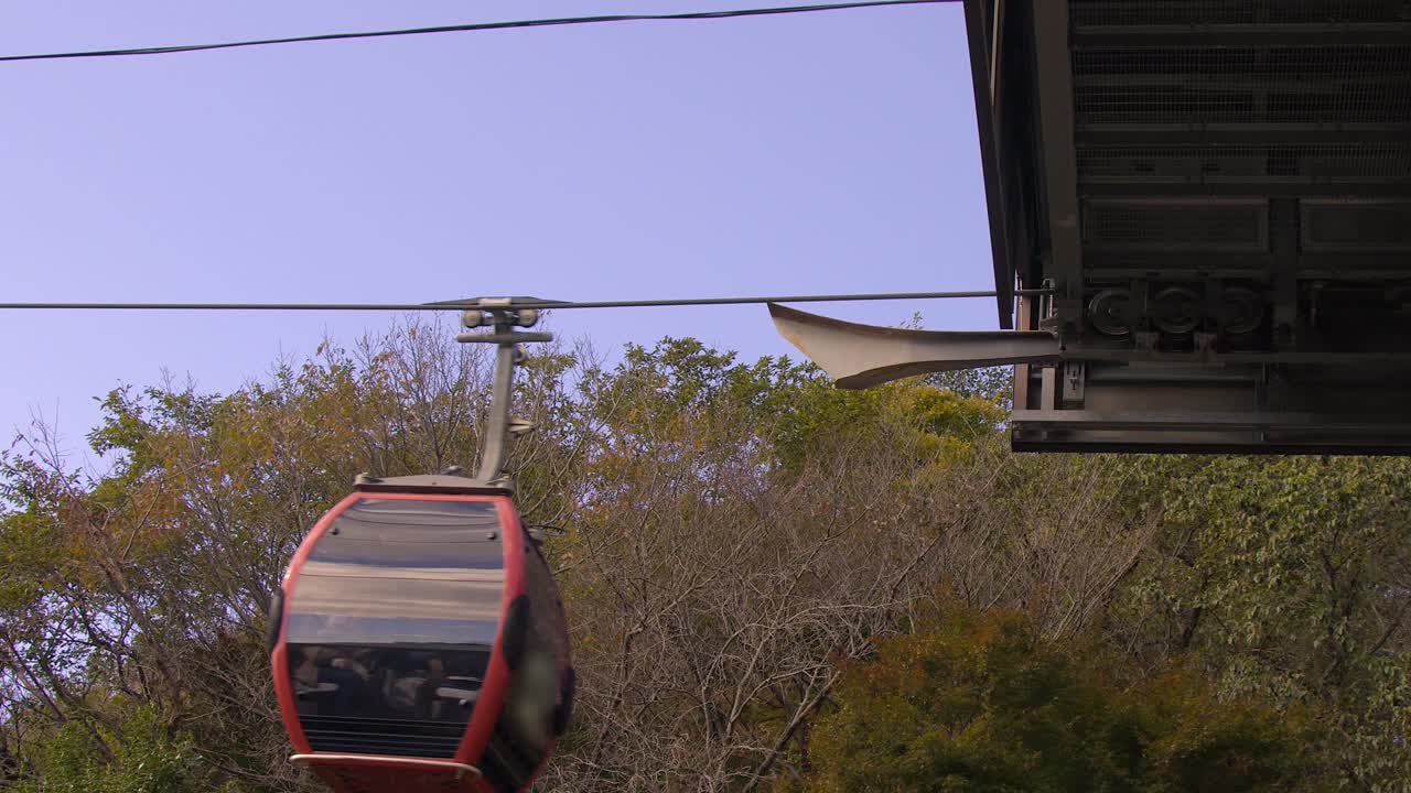 La cabinovia rossa arriva alla stazione in vetta tra il fogliame autunnale