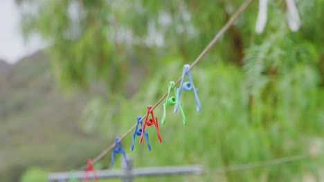 disparo de cerca de pinos de telas de varios colores colgando de un cable en el campo en una granja