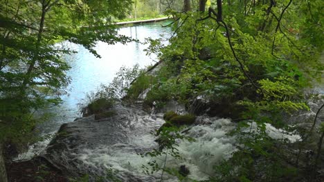 Cascading-waterfalls-flowing-into-a-turquoise-pool-near-a-boardwalk-at-Plitvice-Lakes-National-Park-in-Croatia,-Europe-at-¼-speed