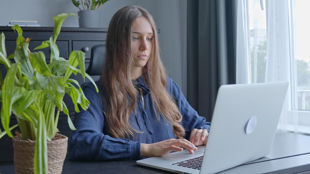 Cute young caucasian woman concentrating on working with laptop at office desk