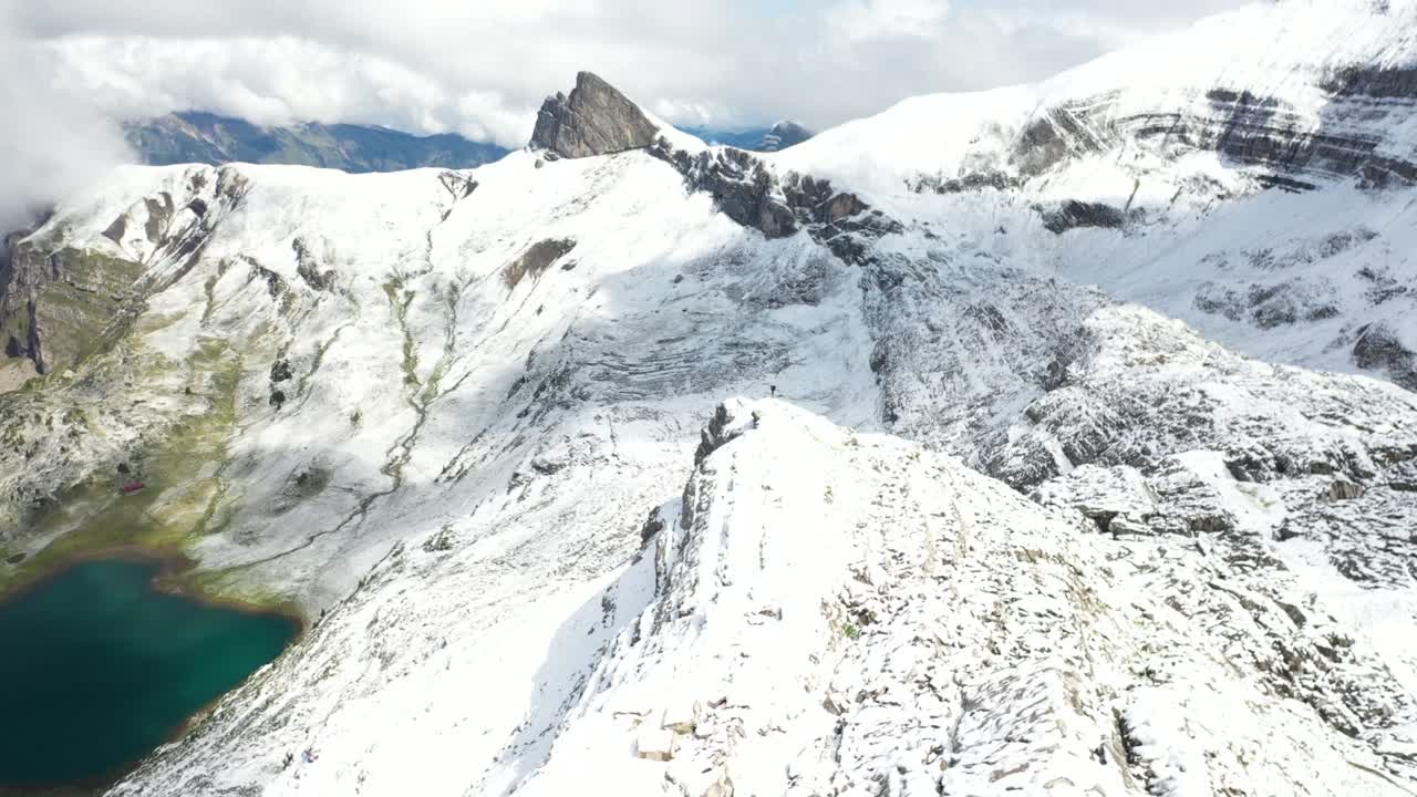 disparo de dron volando rápido hacia adelante a lo largo del borde del acantilado empinado con un hombre parado solo en el borde mirando el paisaje épico y dramático