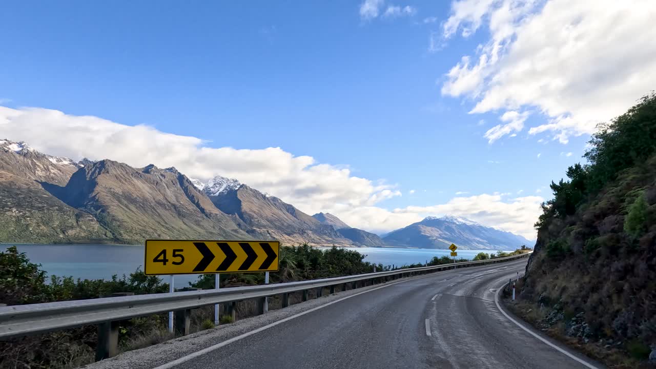 A breathtaking drive along Queenstown's mountain roads, showcasing stunning lake views and dramatic landscapes under clear skies