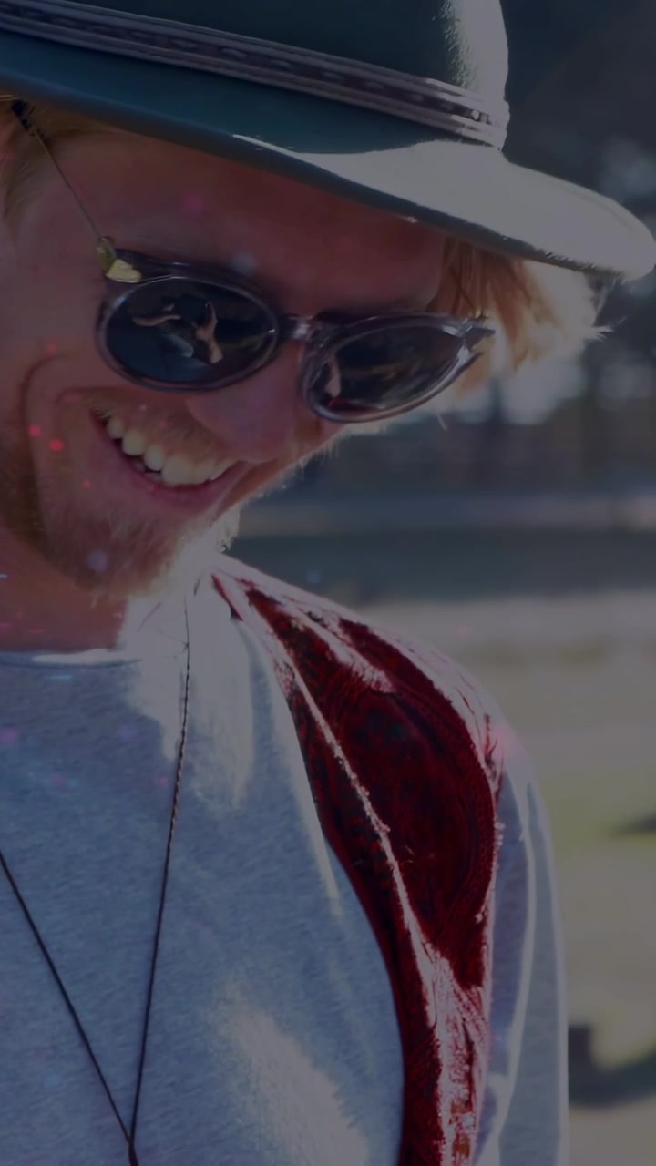 Video verticale: Uomo che tocca il telefono, mostrando icone animate intorno a cappello e occhiali da sole, sorridendo per scopi di marketing