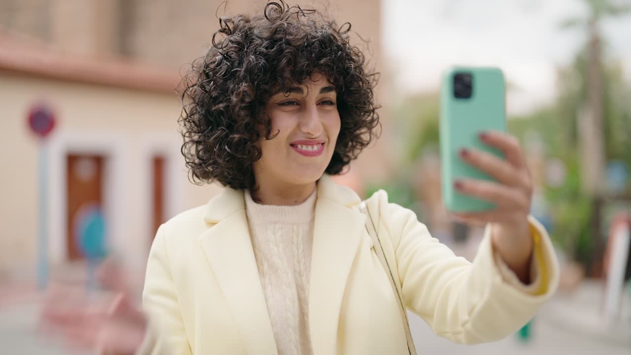 joven sonriendo confiada haciendo una llamada de video en la calle
