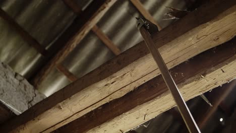 a farmer hangs a scythe on the beam of an old brick barn