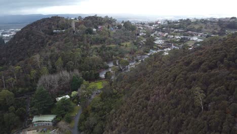 un dron de 4k volando sobre una montaña hacia una pequeña ciudad australiana en tasmania.