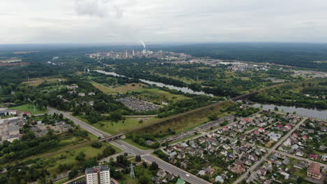 Stadtbild-Von-Jonava-Und-Gebäuden-Der-Chemischen-Industrie-Mit-Rauchenden-Schornsteinen-Am-Horizont,-Luftdrohnenansicht