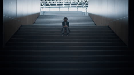 unhappy schoolboy sitting staircase alone close up. lonely bullies victim hiding