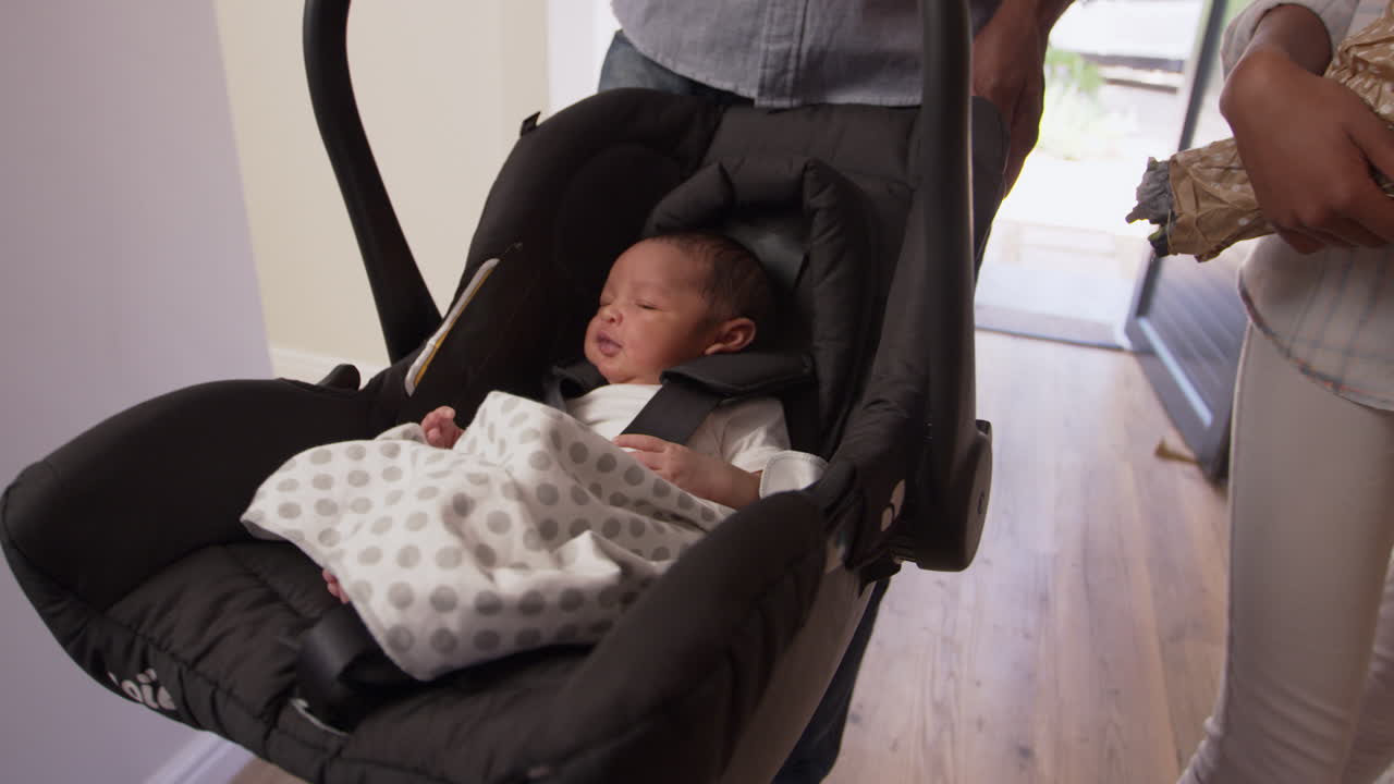 Parents Arriving Home With Newborn Baby In Car Seat