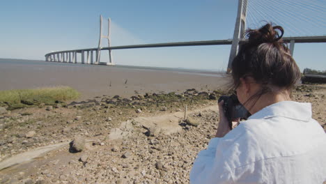 young woman taking a photo of the tagus river and vasco da gama bridge in lisbon, portugal