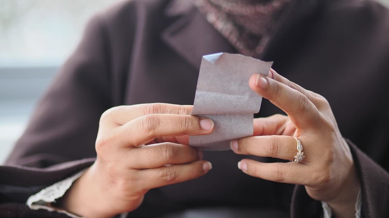 Close Up of Hands Folding a Small Paper Receipt